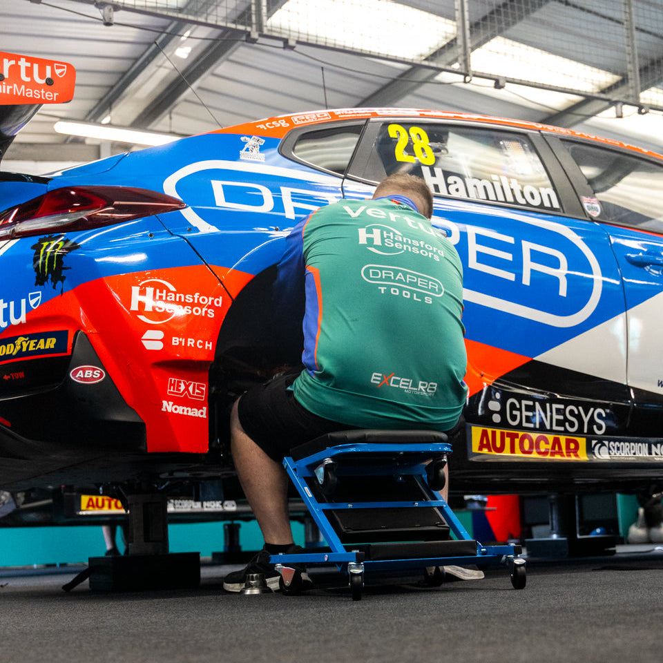 A race car mechanic sat up on the Car Creeper & Seat by Draper tools