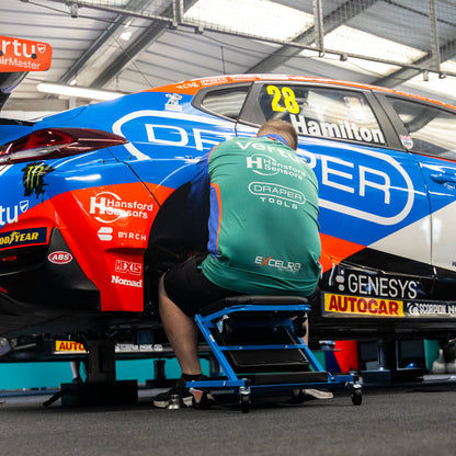 A race car mechanic sat up on the Car Creeper & Seat by Draper tools