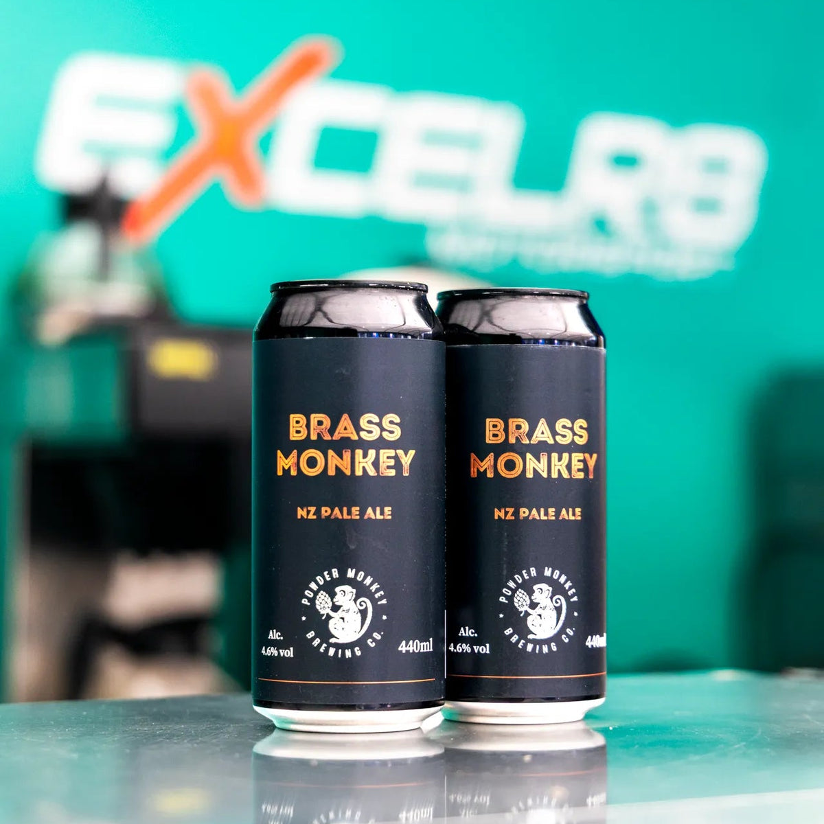 Two cans of Brass Monkey NZ Pale Ale standing on a reflective surface