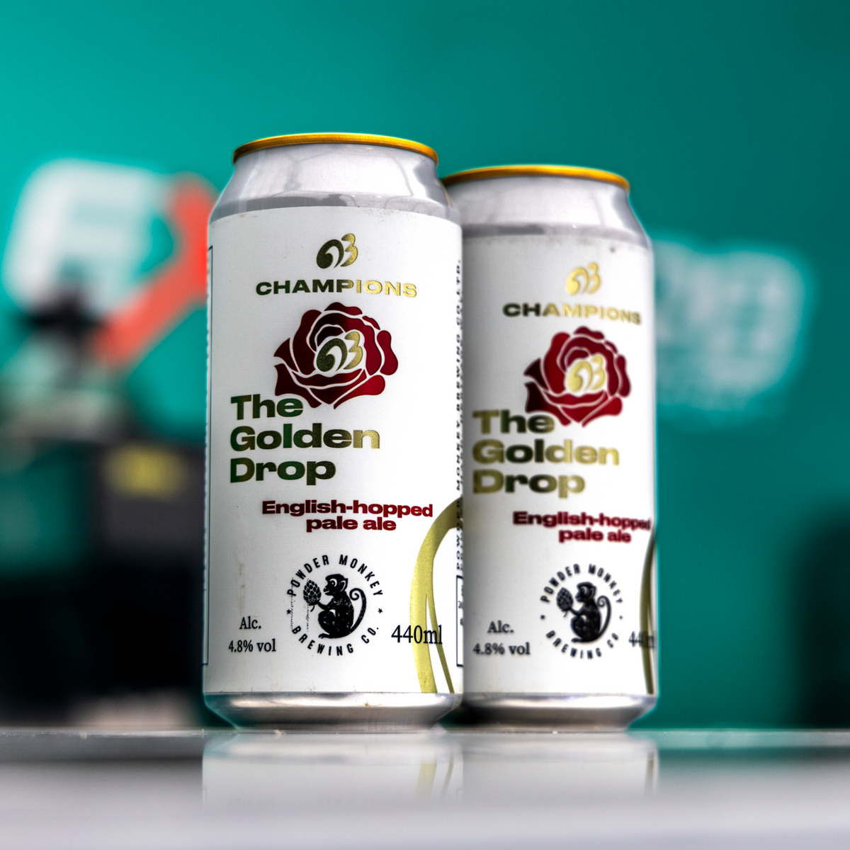 Two cans of Champions The Golden Drop English-hopped pale ale are standing on a reflective surface