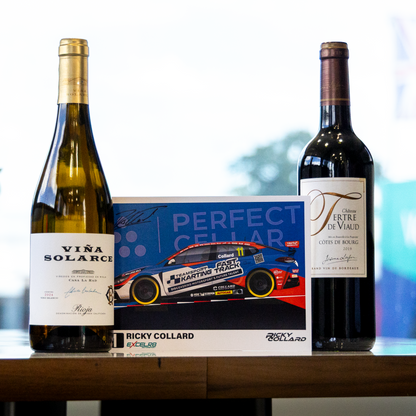 Two wine bottles and a branded display card arranged on a tabletop in a bright indoor setting. The left bottle is a pale green glass bottle labeled VIVA SOLARI, the right bottle is a dark red wine bottle with a label starting with FF, and the center card reads PERFECT CELAR and features a race car with Ricky Collard branding.