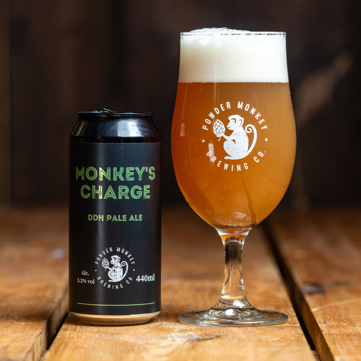 A can and a glass of beer on a wooden table. 